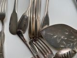 many spoons and forks laid out on the table