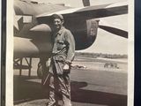a black and white photo of a man standing in front of an airplane