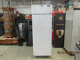a refrigerator in a warehouse with other appliances in the background