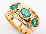 an image of a close up of a gold ring with green stones