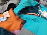 a pile of clothing that includes a jacket, a jacket, and a hoodie