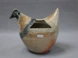 a bird shaped vase with a lid on a table
