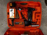 une mallette à outils orange, contenant des outils, posée par terre