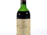 une vieille bouteille de vin posée sur une surface blanche
