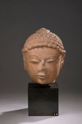 tête d'une statue de Bouddha posée sur un socle noir
