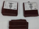 Trois serviettes marron sont posées sur une nappe blanche