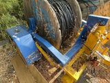 a blue and yellow plow sitting on the ground next to a wooden fence