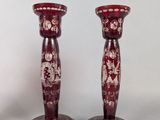 pair of red glass candlesticks with floral designs on them