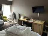 a bedroom with a bed, desk, chair and television