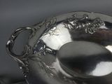 a silver plate with a spoon in it on a table