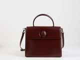un sac à main marron posé sur une surface blanche