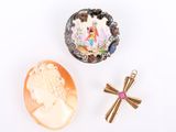 three pieces of jewelry including a cross, a shell, and a broochet