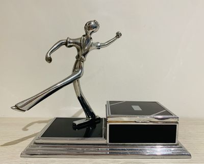 statue of a man holding a tennis racquet on top of a wooden table