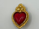 a close up of a red heart shaped broochle on a white surface