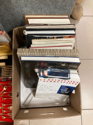 une boîte remplie de livres posée par terre à côté d'une chaise