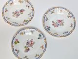 three plates with floral designs on them sitting on a white surface
