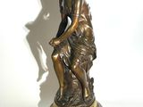 bronze statue of a woman sitting on a rock with a bird in her hand