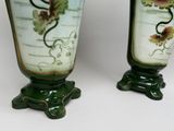 two vases with flowers painted on them sitting on a table