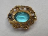 une image représentant une broche en or sertie d'une pierre bleue