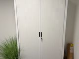 une armoire blanche dans un coin de la pièce, avec une plante dans ce coin-là