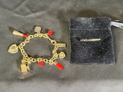 bracelet orné de breloques rouges et dorées, accompagné d'une pochette en velours noir