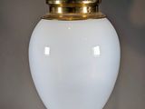 a white lamp hanging from the ceiling with a gold crown on top of it