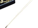 Collier avec un crâne et des os croisés plaqué or, présenté dans un coffret en velours noir