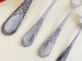 four silver spoons and two silver spoons on a white table
