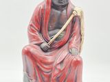 statue of a man sitting on a rock holding a stick