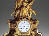 a gold clock with a statue on top of it