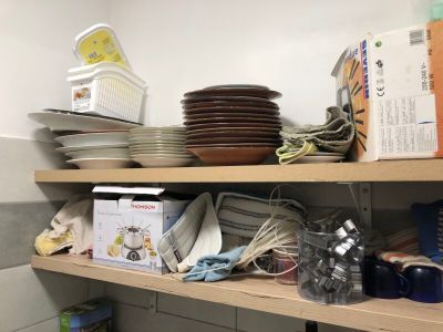 many plates and pans on the shelves in the kitchen