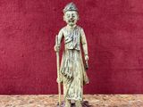 an old statue of a woman with a cane stands on a table