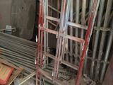 a pile of metal pipes and a ladder in a room