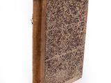 an old book with a brown cover on a white surface