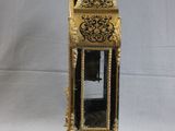 a gold and black clock sitting on a white surface