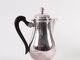 a silver coffee pot with a black handle on a white background