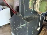 a machine that is sitting on the ground next to a pile of wood