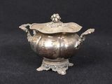 an antique silver plated teapot on a stand with a black background