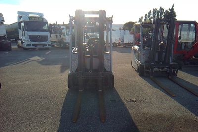 two forklifts parked in a parking lot with other trucks in the background