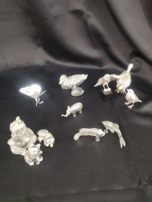 a lot of silver figurines sitting on a black cloth