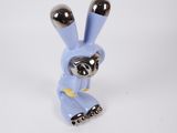 a close up of a small blue rabbit figurine on a white surface