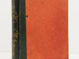 an old book sitting on top of a white table next to a white wall