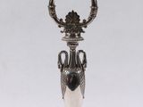 a silver plate with a vase on top of it on a table