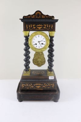 une horloge noire et dorée posée sur une table blanche