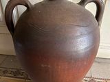 a large brown vase sitting on the floor in front of a door