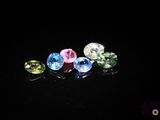 un gros plan sur un ensemble de pierres précieuses de différentes couleurs posées sur une surface noire