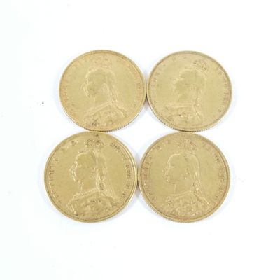 quatre pièces d'or « sovereign » empilées les unes sur les autres sur une surface blanche