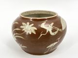 a brown vase with white designs on it on a white surface