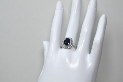 une bague sur la main d'un mannequin, sertie d'une pierre bleue