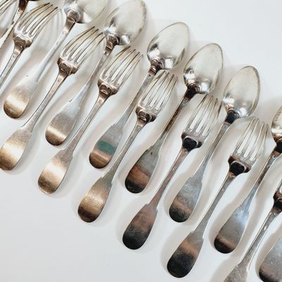 a lot of silver spoons and forks on a white table